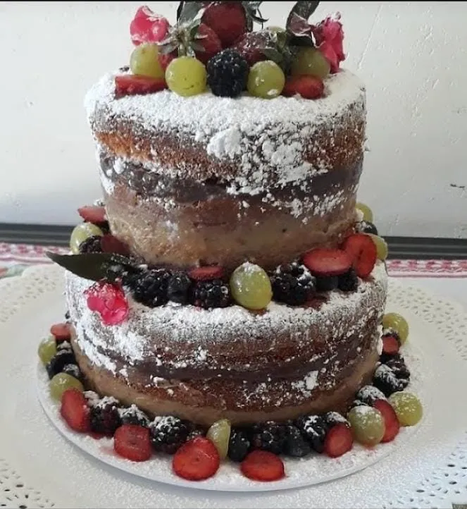 Bolo naked cake de dois andares decorado com frutas vermelhas, uvas e açúcar de confeiteiro