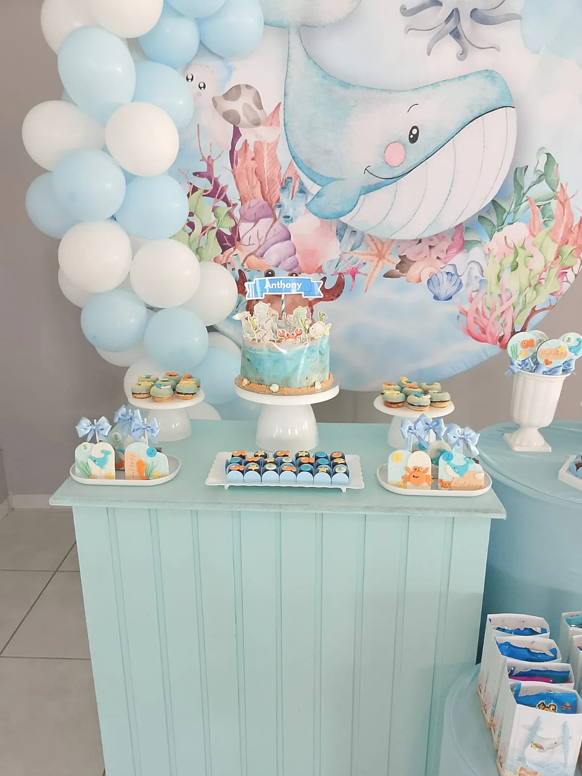Mesa de doces com tema fundo do mar, bolo central, cupcakes, brigadeiros e decoração com balões